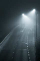 Empty road and streetlights at foggy night