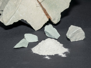 Zeolite natural  raw stones and powder on black stone  background.Selective focus