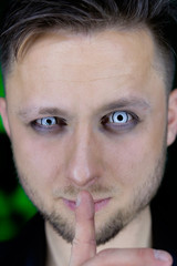 Obraz premium man holding finger near mouth in silence gesture manner