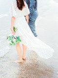bride and groom on the beach with wedding bouquet