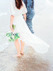 bride and groom on the beach with wedding bouquet