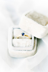 Golden ring with blue stone in velvet ring box