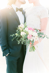 Mid section of bride and groom with flower bouquet