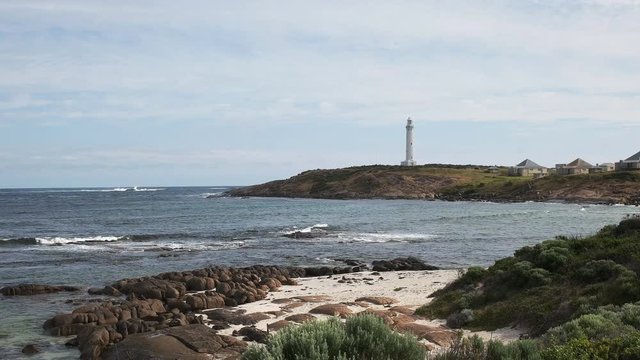 a beach and rocks at west australia's cape leeuwin lighthouse, situated at the most south westerly tip of australia, standing at the point where the indian and southern oceans meet