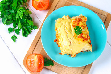 Traditional Italian pasta cannelloni. Baked tubes stuffed with minced meat with parmesan cheese and bechamel sauce on a white wooden table.