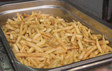 Tray of cooked French fries in silver serving dish