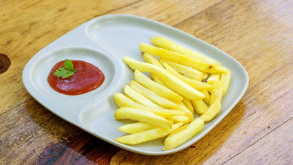 ketchup and french fries on a wooden table.