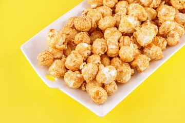 Popcorn with caramel on yellow background