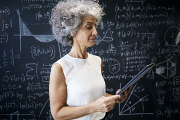 Middle aged academic woman working at blackboard