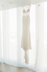 Lace wedding dress hanging in window