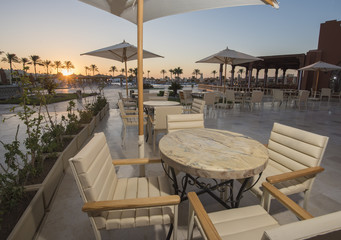 Outdoor terrace area with tables in a tropical hotel resort at sunrise