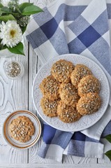 On a plate oatmeal cookies with seeds, white light wooden background