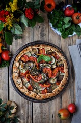 On a wooden table on a plate of vegetable gallet from tomatoes, eggplant, courgettes and bell peppers. Style Rustic