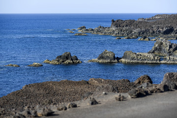 Fototapeta na wymiar Volcanic rocks protruding from the assessment at the coast of the island of Lanzarote