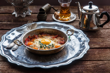 Copper pan with fried eggs and sausages, turkish style