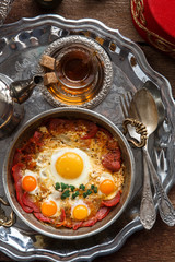Turkish cured beef and fried eggs in copper pan, traditional breakfast, top view