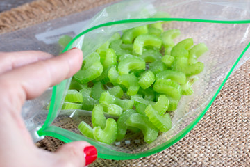 Frozen pieces of celery in a bag on a wooden board