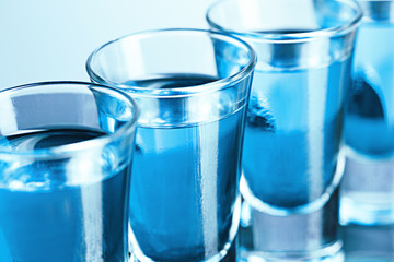 Vodka glass with ice on blue background