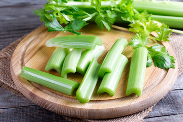 Stalks of celery on a wooden cutting board on a table