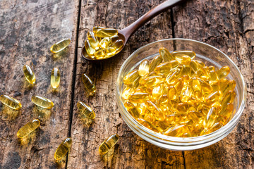 plate with capsules of fish oil on a wooden background