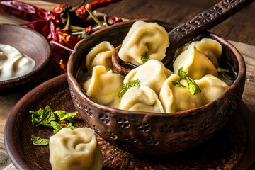 Russian dumplings with meat and broth and herbs in a rustic style