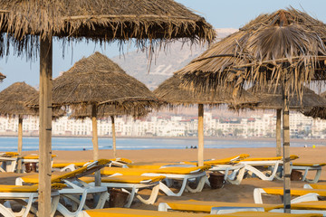 Naklejka na ściany i meble Beach loungers and umbrellas on the sea. Main beach in Agadir city located on the shore of the Atlantic Ocean.Morocco.