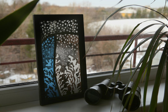 Stained glass with frosty drawing on windowsill. Handmade stained glass graphic pictures.