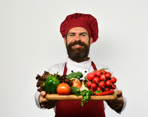 Happy chef holding board with fresh vegetables