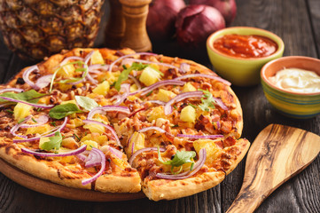 Homemade hawaiian pizza on black wooden background.