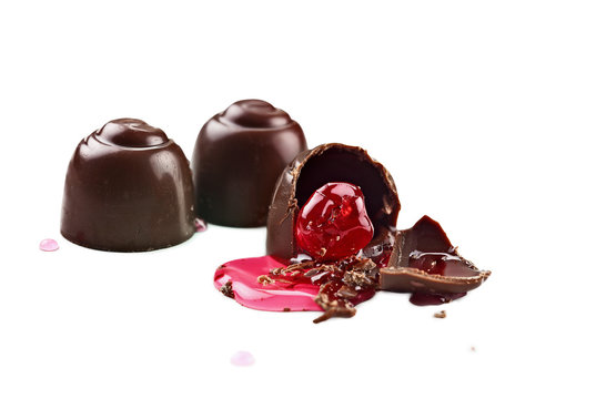 Three chocolate covered cherries isolated over white background with clipping path included. Shallow depth of field with selective focus on bitten portion of truffle with exposed cherry.