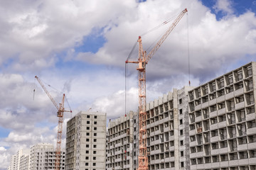 Fototapeta na wymiar Construction cranes and multi-storey houses under construction