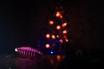 Christmas toys on table at decorative fir-tree blurred with lights. Making a Christmas tree on table. Empty space. Useful as greeting card.