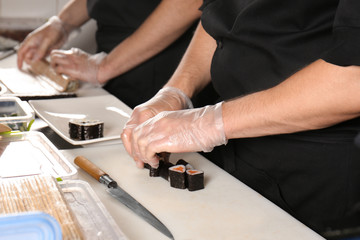 Obraz na płótnie Canvas Chef making tasty maki rolls in restaurant