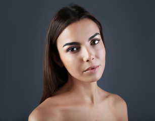 Naklejka premium Beautiful young woman with eyelash extensions on grey background