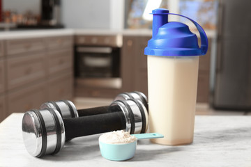 Composition with protein powder, shake and dumbbells on table