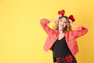 Attractive young woman with red hearts on color background