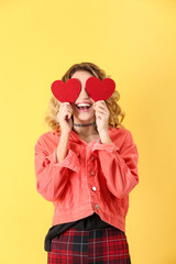 Attractive young woman with red hearts on color background