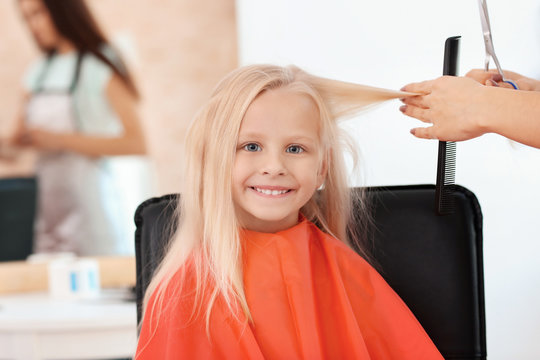 Female hairdresser working with little girl in salon, closeup