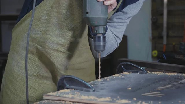 Side view of carpenter drilling a wood plank, closeup slow motion.