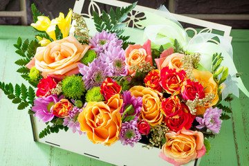 Background wedding or Valentine's Day. Basket bouquet of roses and chrysanthemums on a vintage wooden background.