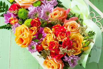 Background wedding or Valentine's Day. Basket bouquet of roses and chrysanthemums on a vintage wooden background. Space for your text.