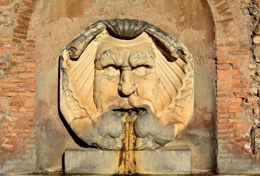 Beautiful fountain in orange gardens in Rome, Italy. Is this wonderful fountain of a giant, grotesque mask, which spits water into a giant, ancient Roman basil.