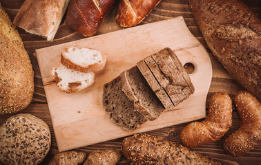 Many mixed baked breads and rolls on rustic wooden table