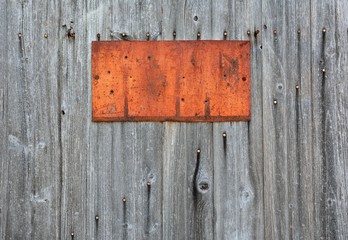 Rusty metal sign on wooden wall.