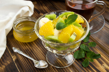 Healthy breakfast:fruit salad,honey and tea on the  wooden background