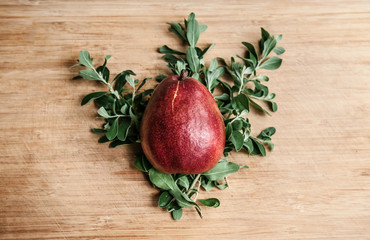Fresh ripe red pear on pine leaf wooden background, top angle