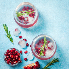 Winter Sea Breeze holiday pomegranate rosemary cocktail on light blue background. Top view, space...