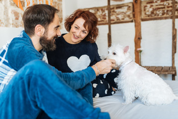 Couple relaxed at home in bed with the dog .