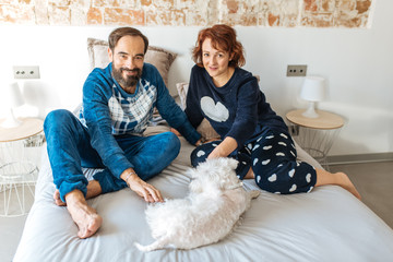 Couple relaxed at home in bed with the dog .