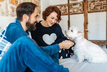 Couple relaxed at home in bed with the dog .